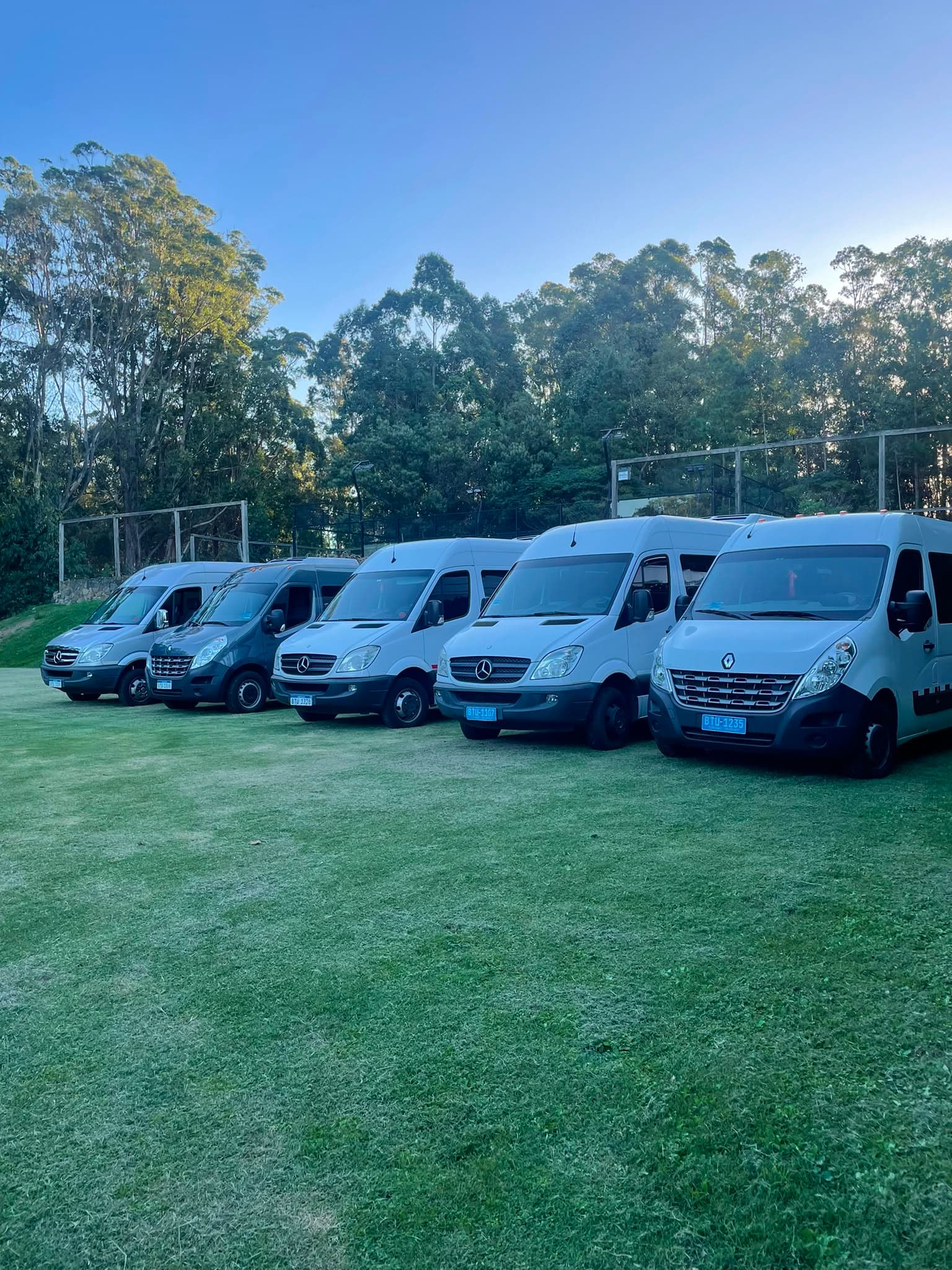 Flota de minibuses de Tino Viajes junto a una cancha de fútbol